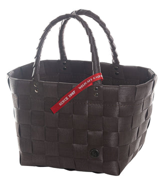 Der Witzgall Einkaufsshopper Mini 5008-03/0U Aubergine ist ein geflochtener brauner Korb mit zwei Henkeln, gefertigt aus strapazierfähigen Kunststoffbändern, versehen mit einem roten Schild mit der Aufschrift „SINCE 1907“.