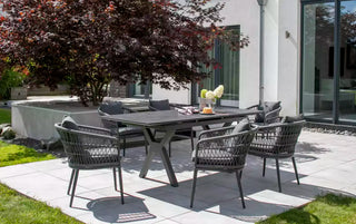 Essbereich im Freien mit einem wetterfesten DeVries Ausziehtisch Hammond 160/210x90cm dunkelgrau mit Aluminium-Gestell und sechs Korbstühlen auf der Terrasse. Ein roter Ahornbaum und Glastüren vervollständigen das elegante Ambiente.