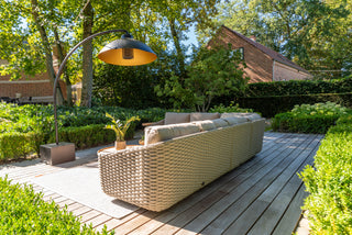 Das Zeo Living 4Seasons Lounge-Set Casanova Rope Latte schafft mit seinem geflochtenen Sofa mit Seildetails einen gemütlichen Rückzugsort im Freien, aufgewertet durch eine schicke Stehlampe und Topfpflanze auf dem Holzdeck. Umgeben von Bäumen und Büschen sorgt es mit seinen bequemen, wetterfesten Kissen für Ruhe.