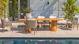 Außenterrasse mit einem 240 x 110 cm großen Teakholztisch 4Seasons Tisch Capri und sechs gepolsterten Stühlen am Pool, umgeben von Topfpflanzen.